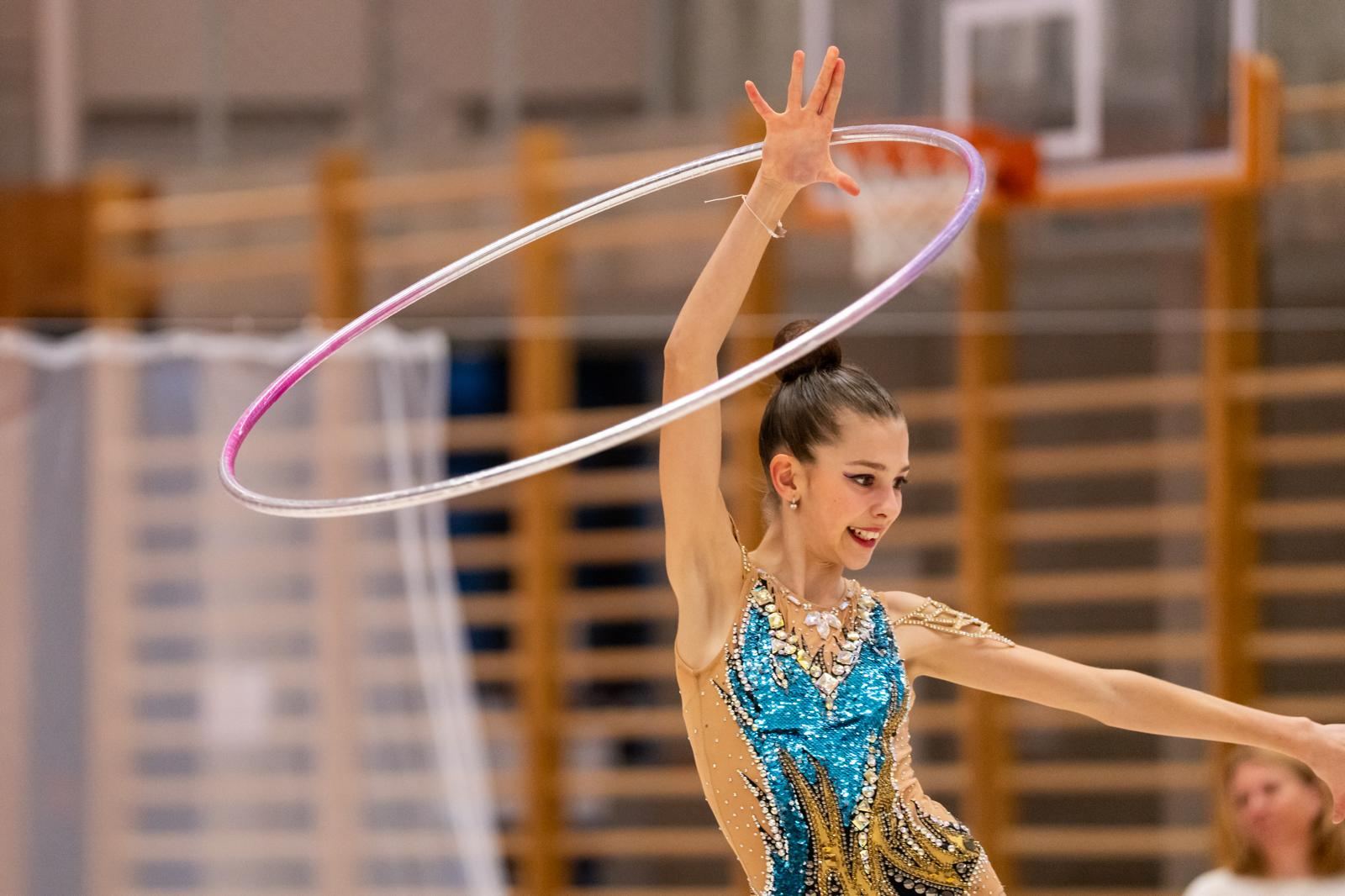 Gymnastka v tyrkysovém dresu s obručí nad hlavou